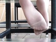 young blonde show feet in pantyhose on table