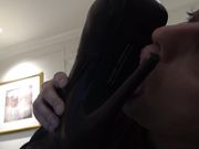 Val�s thigh high boots are cleaned to a high shine by the slave�s tongue